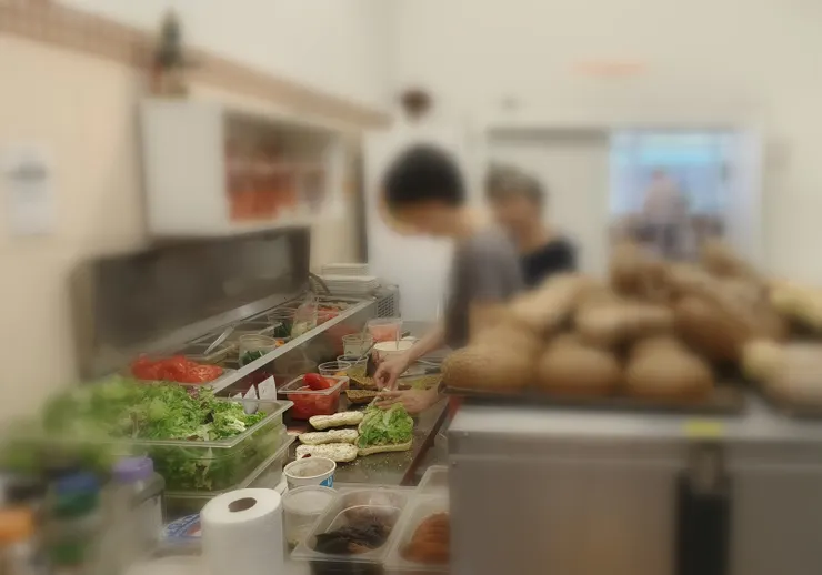 【招呼顧客沒時間為離別感到酸楚 百忙中蘭妲堅持為遠行客做漢堡！現做漢堡是熱賣商品，雖然忙得團團轉，蘭妲仍執意為我們各做一份帶上火車。】