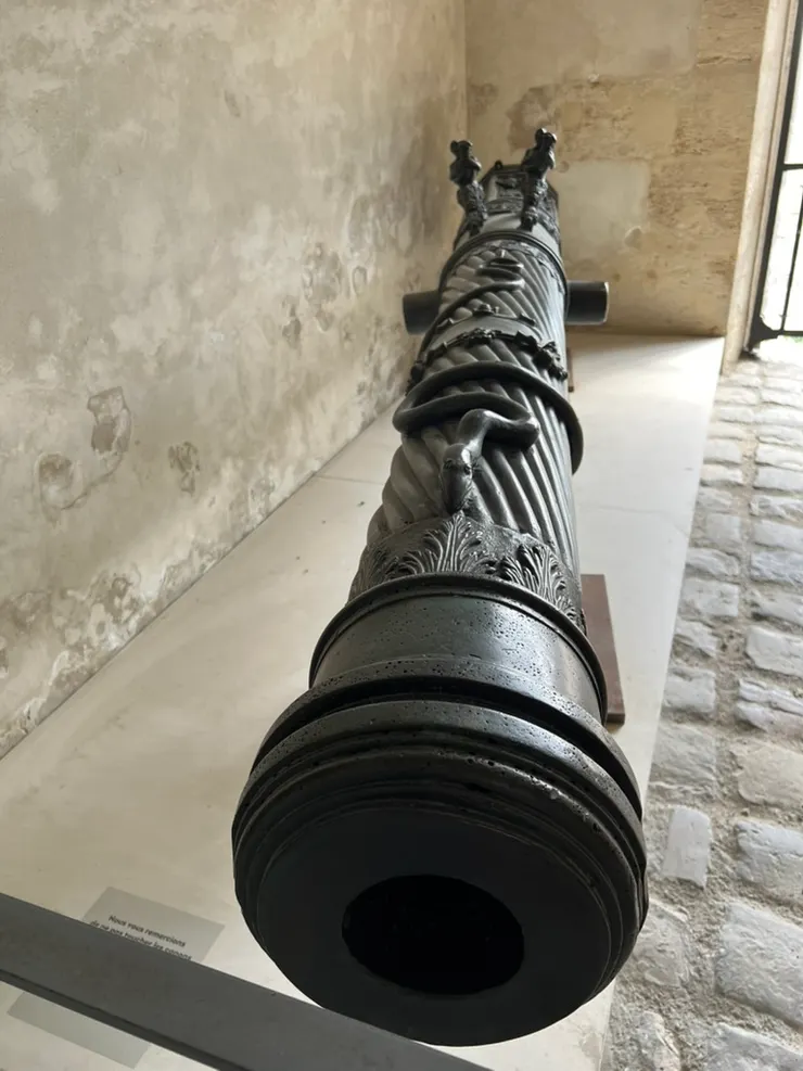There is a snake on top of the cannon. What are the two figues in the back? 上方有一條蛇纏著，後面的兩個把手呢？