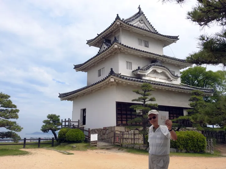 拿著百大名城集章本和丸龜城迷你小天守合影
