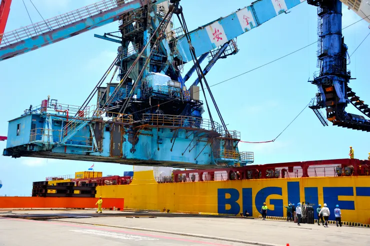 【緩緩將卸煤機移向碼頭!因為端末欄杆妨害著陸,準備先行切除,岸上好些工作人員仔細觀察,決定切割點。】