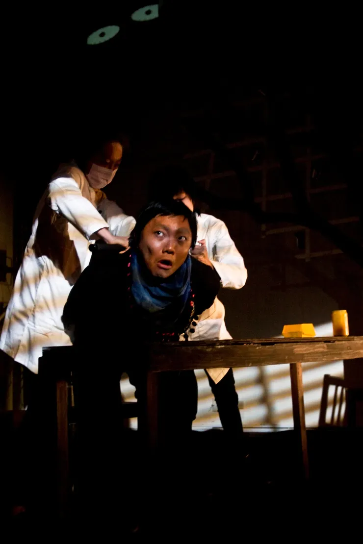 ▲劇中哥哥受到審訊的場景,用一張桌子和幾張椅子擺放出所有場景,道具全部漆成黃色。(演員左至右:朱家儀、黃兆嶔、謝靖雯)