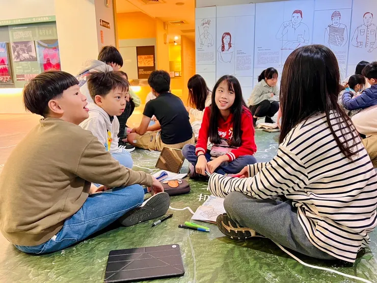 在新竹縣史館席地而坐，討論著等等要如何合作探索歷史的學生們。