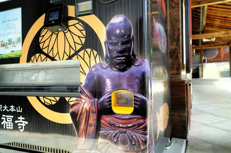 以羅怙羅尊者像為主題的自動販賣機退幣口。