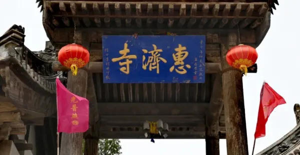 慧濟寺的正門上掛著藍色的匾額,上面書寫著「惠慈寺」字樣,兩側紅燈籠掛在門柱上,增添了幾分莊嚴與神聖。