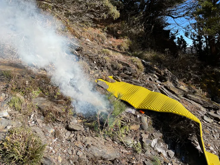 1月30當天吸引直升機注意的兩樣工具。亮色睡墊吸睛，而往火堆裡丟生的枝葉可以製造狼煙，但小心不要把火悶熄了。