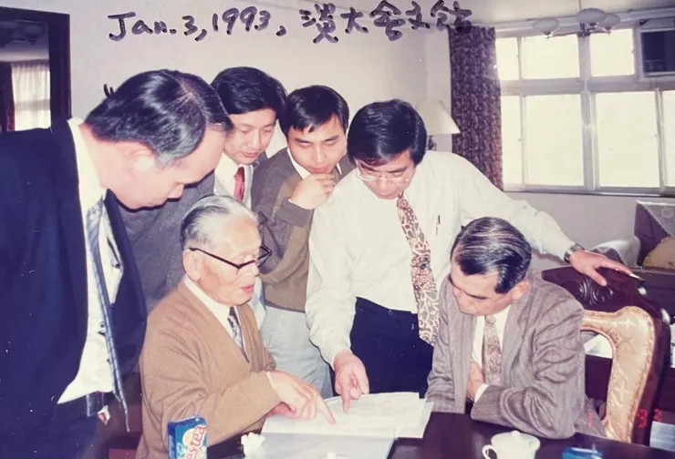 野副鐵男院士與林雲山校長坐在桌前指導研究生。立者左二起:林稟彬博士、林世智博士、守田忠義博士。坐者左起:野副鐵男院士、林雲山校長。(拍照日期1993 年元月3日於淡水淡江大學會文館) 