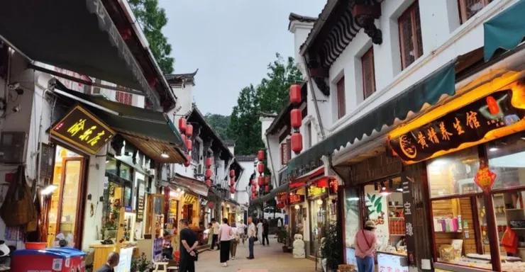 九華街道的熱鬧場景,街道兩旁的商店燈火通明,紅燈籠懸掛其間,遊客在石板路上漫步,呈現出一派繁華的街景。