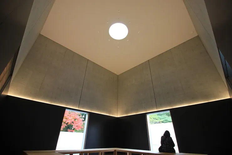 光之室內，在幾何斜牆與椅子之間，坐在窗前的觀者，成為空間沉思的一部分。