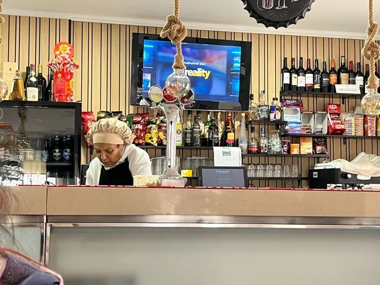 表情嚴肅但人很好的老闆娘，在櫃台後忙碌著。