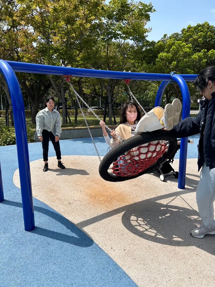 雅惠老師和Tony老師與學生盪鞦韆的互動畫面。兩位老師在笑聲中一前一後的推著鞦韆。