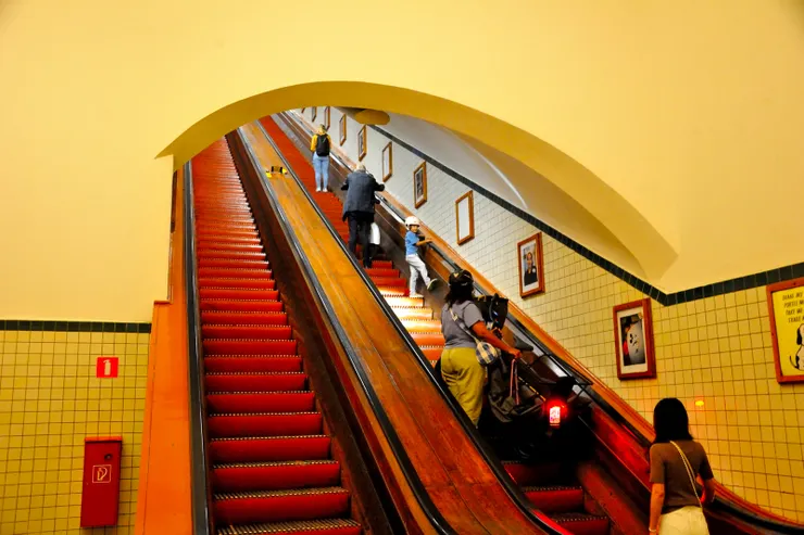 【搭木製老電扶梯河底隧道來回走！搭這精緻的古董木電扶梯通出入聖安娜隧道(St. Anna's Tunnel)。扶梯兩旁掛有圖片講述隧道歷史。】