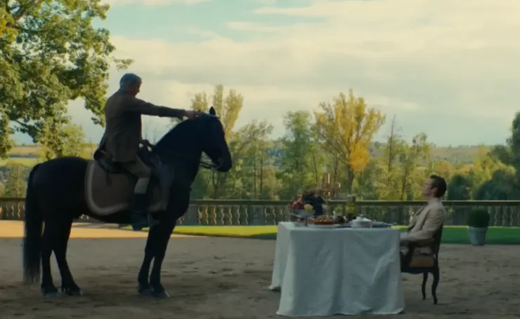 餐桌與槍口的對峙，象徵著權力遊戲的荒謬。