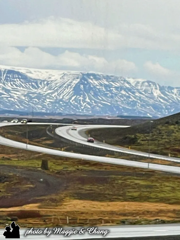 車窗外的風景從灰白城市漸漸轉為荒涼與壯闊。冰島的山景如畫，車子沿著南岸公路奔馳，路邊是覆雪的火山、黑色的熔岩地、偶爾冒出蒸氣的地熱田，這個國度有種不合時宜的寂靜與宏大，讓人看著看著，心也靜了。