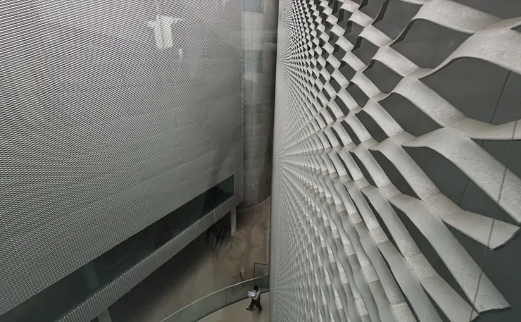 金屬擴張網穿孔牆面與弧線結構，綠美圖外觀如流動的建築藝術品