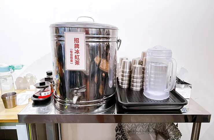 小白拉麵店內的自助飲料區，提供免費冰水與冰紅茶，乾淨衛生的不鏽鋼保溫桶，東湖平價餐廳推薦