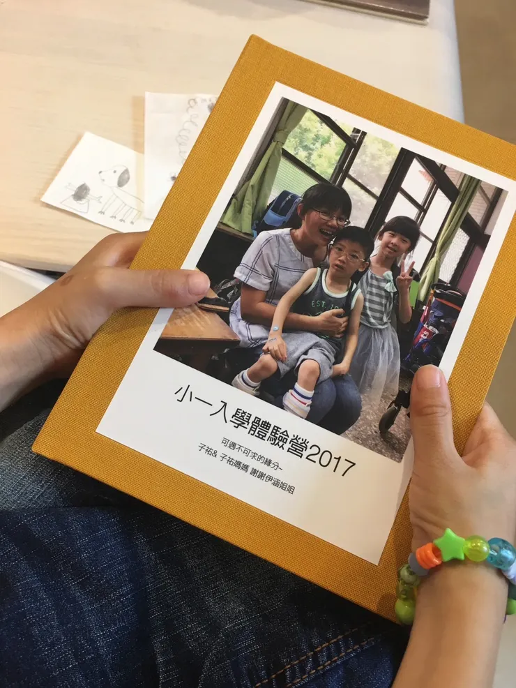體驗營結束後，我做了一本紀念本給對方。祐帶著小女孩製作的手還握著紀念本。