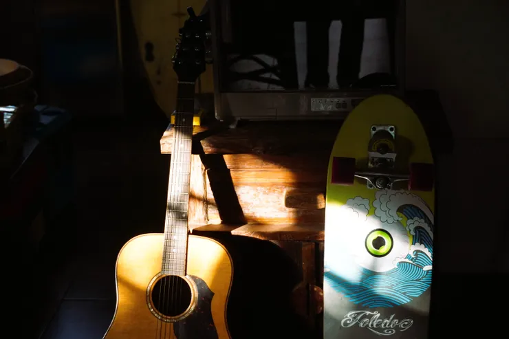 店裡靜靜倚靠在木櫃旁的吉他和衝浪滑板，在夕陽下的光澤柔和又飽滿。