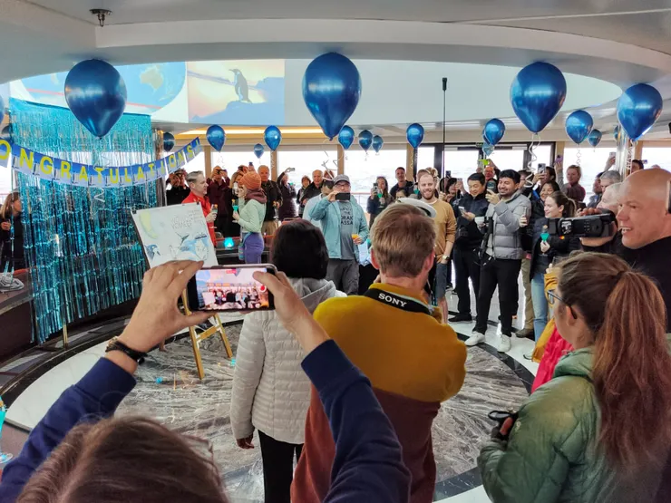 Dome裝飾著氣球彩帶，吊著congratulations!的大字，置有一幅此行預期看到的動物的海報及一幅與World Voyager首次穿越南極圈的大海報。在船長抵達後，大家紛紛在海報前與船長合影留念。