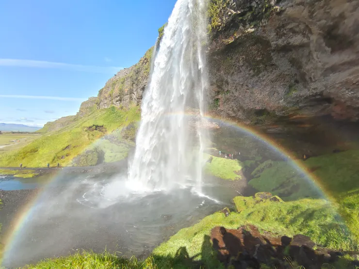 遊客由右側小徑接近瀑布，半圓的彩虹就在咫尺。