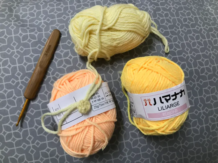 這次用三種顏色鉤毛線花，左下角放在珊瑚橘色毛線上的是淺黃色花心