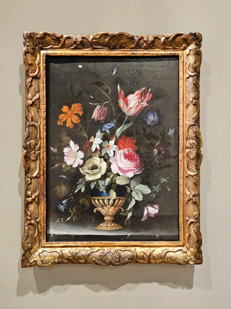 〈花卉靜物〉。混合了不同時期的花種，豐饒靡麗中，花葉邊緣開始泛黃，石板邊上出現裂痕。