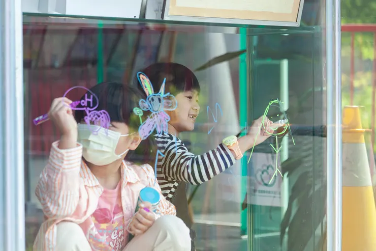 小畫家們在心之谷場館的玻璃上進行彩繪創作