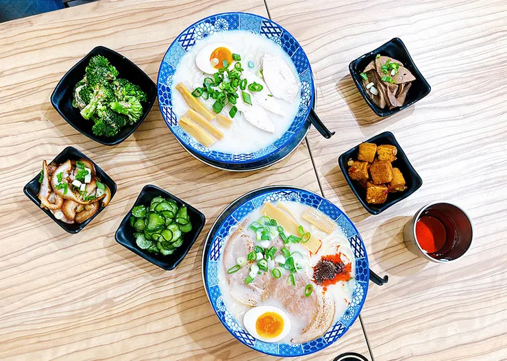 湯匙盛著純白濃郁的雞豚白湯與些許蔥花，展現小白拉麵湯頭溫潤不膩口、雞豚融合的特色。