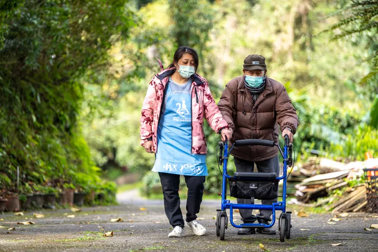 居服員劉素伶陪伴長輩散步，訓練下肢肌耐力。