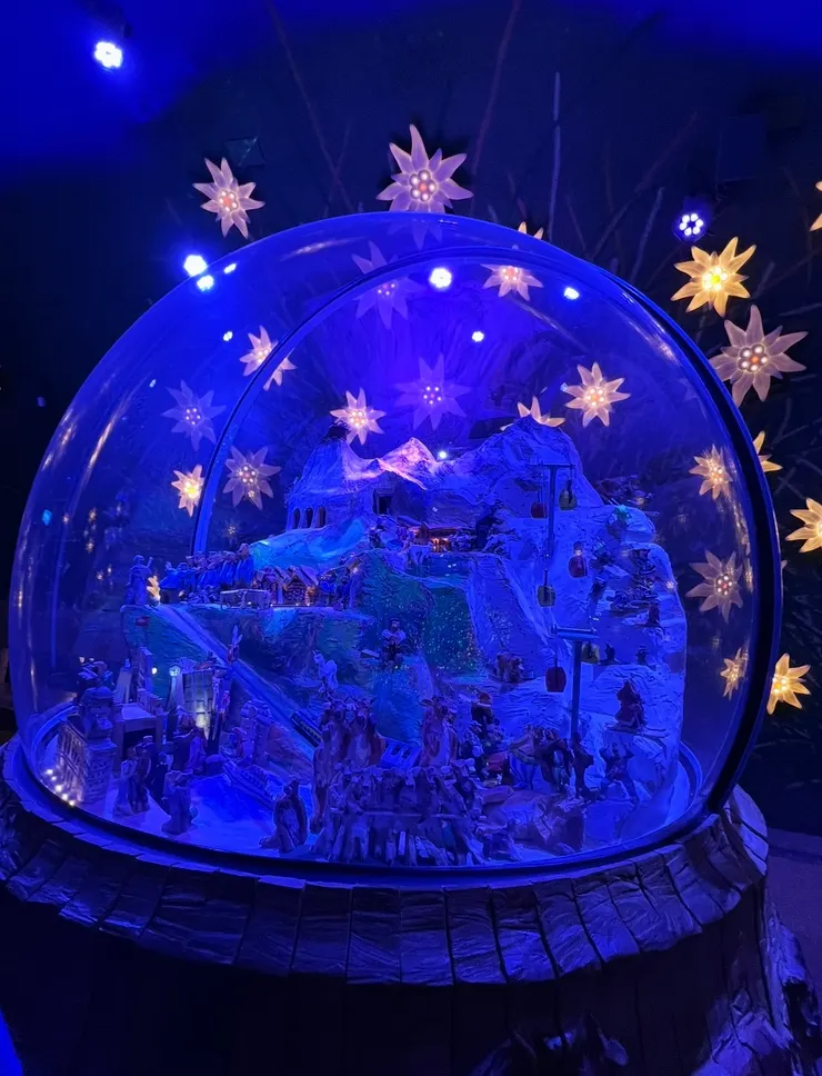 玻璃圓罩裡是少女峰鐵路微縮模型，搭配雪絨花燈飾和藍色燈光，讓遊客感受當年在困苦環境中開鑿鐵路的艱辛