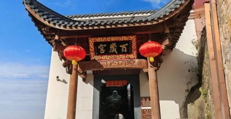 百歲宮的入口，紅色燈籠高懸，匾額上的「宮殿百年」字樣顯眼，精緻的木結構與屋頂勾勒出傳統的建築風格。