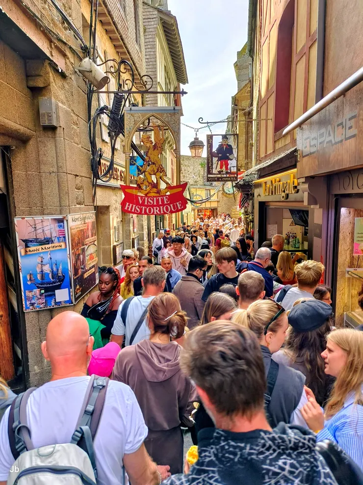 【聖米歇爾山的大街(Grande Rue)，為主要商店街，遊人熙來攘往，兩旁建築保持中世紀風格，多為石造。】