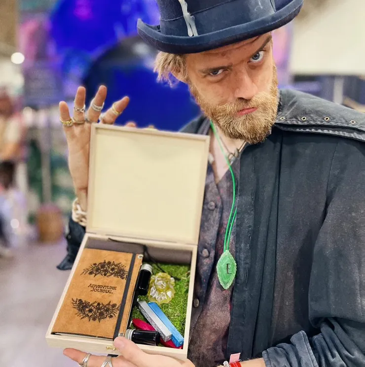 一位扮演商人的劇組成員在展示商品的同時，也配帶著有著清楚E字標示的第四世代永恆項鍊。(圖片來源:Evermore Park, Pleasant Grove, UT. Facebook )