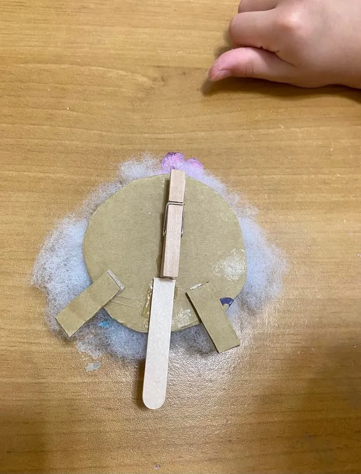 翻到背面,把木夾開口朝上黏在上半部,半根冰棒棍則黏在下半部當作支架。