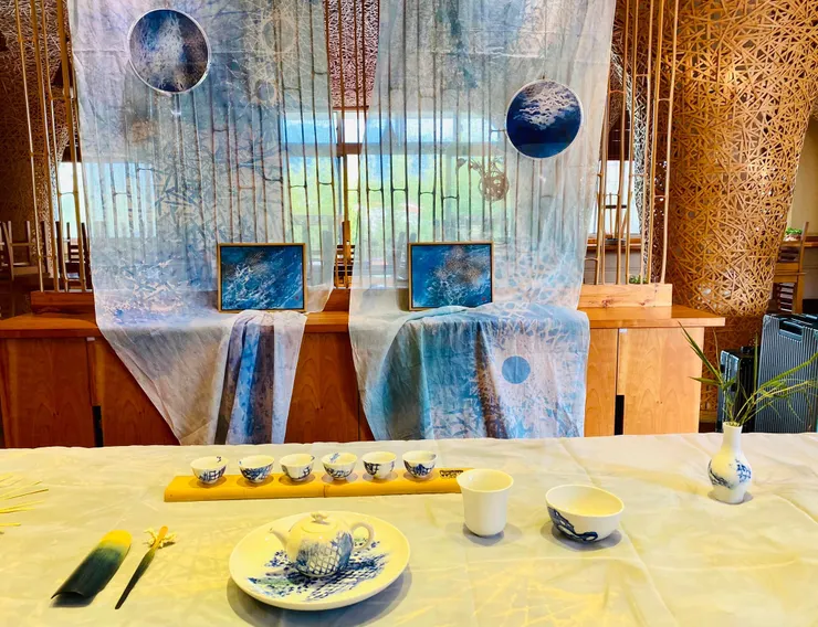 茶席上面的層次,從竹子、染布以及竹篾堆疊出的立體空間的想像,彷彿引領著我們穿越了山林、海邊以及天崖,坐在茶席上望著遠方,視角穿透過室內竹籬笆結構縫隙,對應著戶外搖曳生動竹林。