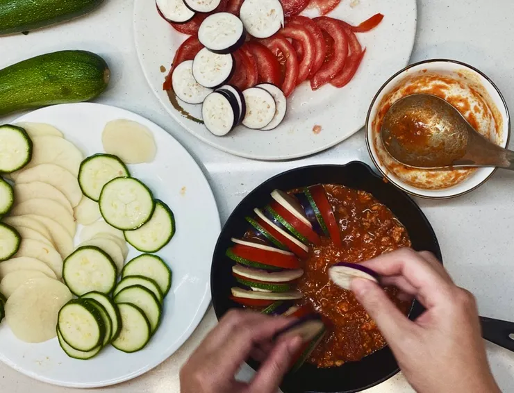 將烤盤或鑄鐵鍋底部鋪滿醬汁，然後依序擺上蔬菜切片，最後撒上橄欖油和黑胡椒便可進入烤箱