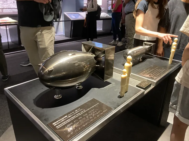 圖為廣島原爆紀念館展示的「胖子」鈽彈 8 分之 1 模型，旁邊的假人為高度示意。
