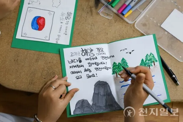 其中一名孩子正在向海洋警察官寫下充滿真心的應援訊息，表達對他們的敬意與感謝。（照片來源：新天地束草教會）