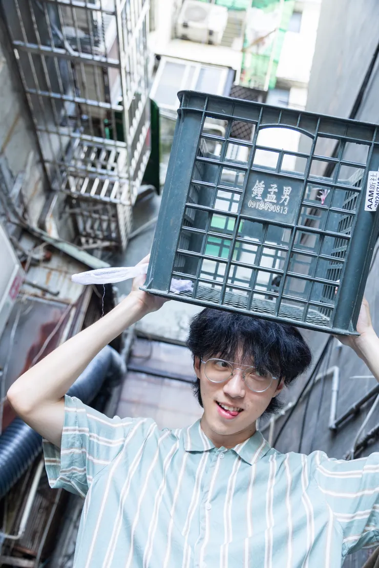 從冷氣室外機旁邊找到置放的籃子，剛好有印主人的姓名，請模特拿起與之互動；背景為台灣生活元素