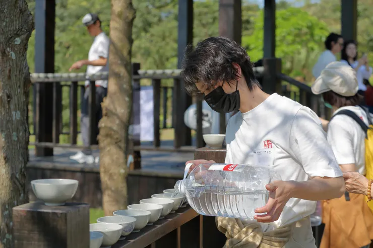 從山泉處提著2個大水桶，準備托水缽加水。