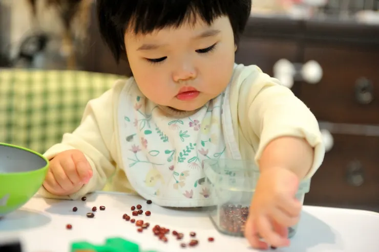 【小傢伙作息正常好帶出乎意料！不怕麻煩的奶奶拿一把紅豆給萬萬玩，訓練指頭靈活度。】