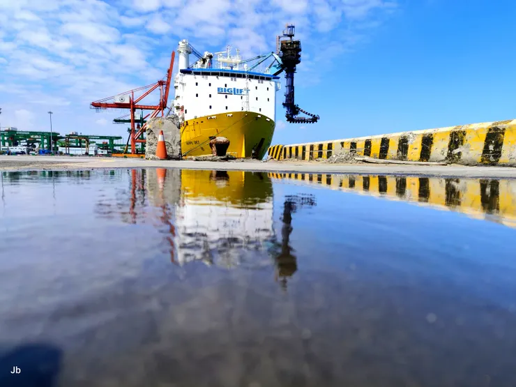 【海吊船如期抵達這過程難得一遇,看你順利離港心中大石總算落地!停在台中港31號碼頭的5號卸煤機,也利用岸邊積水拍個倒影,雖是艷陽天,但有不大不小的風,吹起水波。】