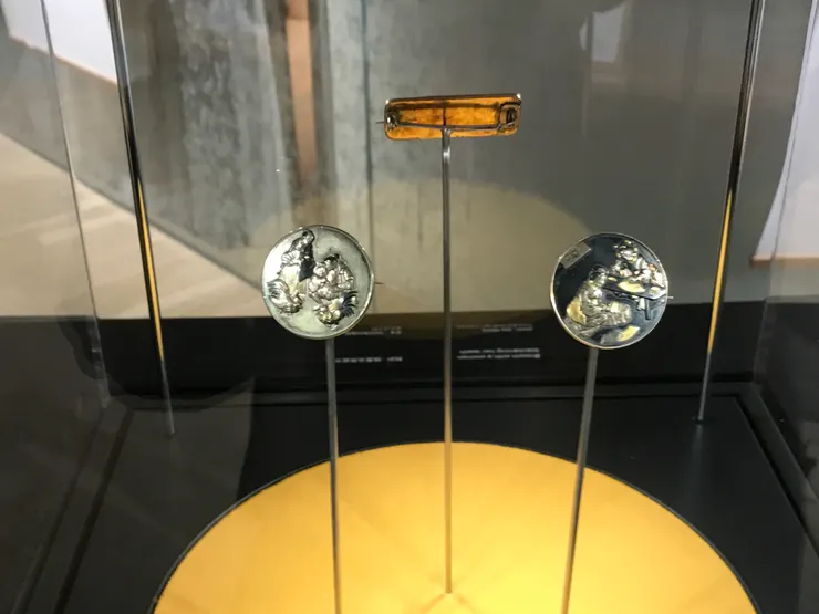 雖然我拍得不清楚，但這兩枚胸針的圖案很反映當時社會的風貌，例如描畫兩名男士觀看鬥雞和造扇的女子。