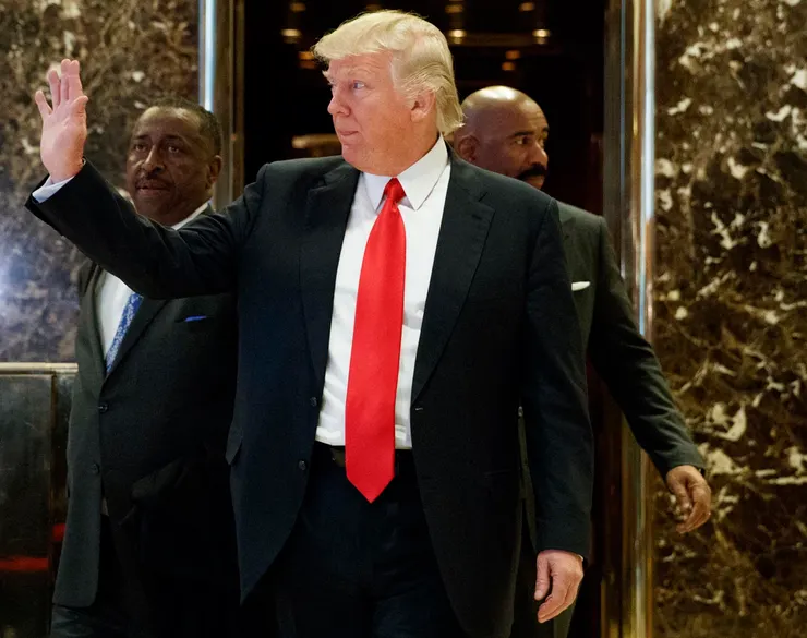 美國準總統川普迅速公布內閣名單，圖為他步出紐約川普大樓金碧輝煌的電梯，向在場人士揮手的資料照。（美聯社）