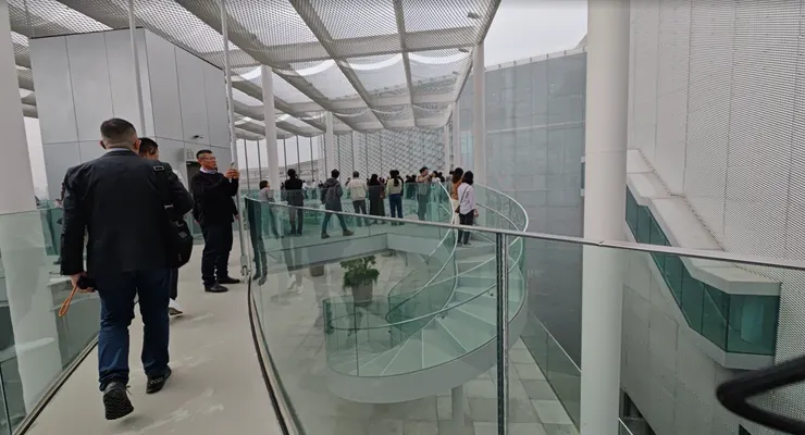 玻璃欄杆與挑空設計讓各樓層視線相互穿透，參訪者沿著弧形廊道漫步，既能俯瞰下方的閱讀區域