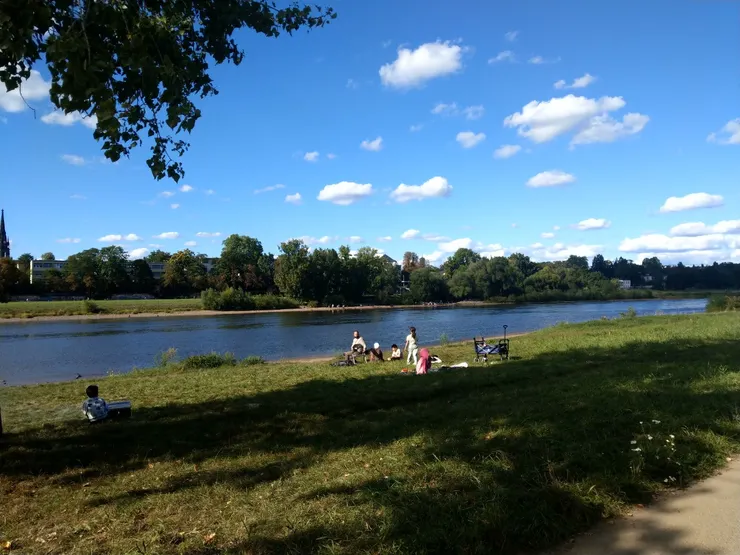 河邊聚集自各國的人們，悠閒地和家人在此聚餐，包含華人