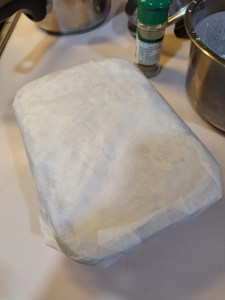 入蒸籠鍋前用烘焙紙蓋上蘿蔔糕，以免蒸煮時產生的水滴落表面，影響口感。