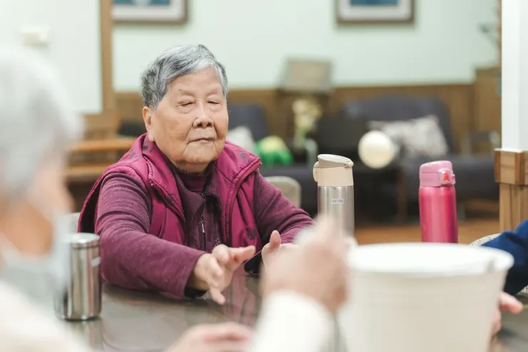 阿嬤玩桌球，將球拋擲入塑膠桶。