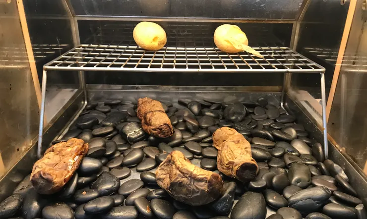 有點冷清的烤地瓜機，剩幾條乾扁的地瓜。架上有兩顆烤馬鈴薯，選左邊沒脫皮的那顆