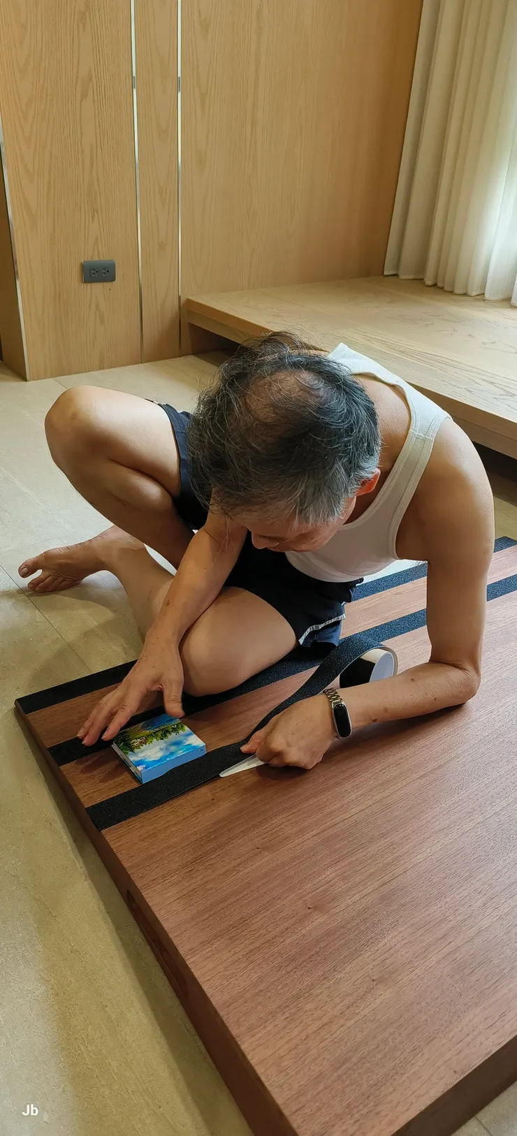 訂購木製輪椅斜板好登上前門落塵區，禿頭老翁正在黏貼金剛砂止滑條。