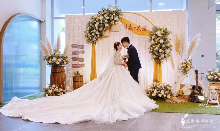 幸福檸檬黃婚禮佈置 @ 台南亞果薈 安妃屈蒂餐廳  在台南的海風與陽光中，亞果薈 安妃屈蒂餐廳見證了無數浪漫時刻。這場以 **「幸福檸檬黃」**為主題的婚禮佈置，運用溫暖明亮的檸檬黃色調，搭配歐式花環與羽毛芒草，營造出陽光般的幸福氛圍。  金黃色的拱門，點綴著飽滿的白玫瑰與香檳玫瑰，配上木桶、燈串與鄉村風擺飾，讓每個角落都成為新人與賓客的拍照打卡點。  「幸福檸檬黃」不只是婚禮顏色，更是一種情感的溫度——象徵喜悅、溫暖與甜蜜。每一次呈現都經過專業團隊的精準擺設，確保現場與範例一致，讓新人在籌備婚禮時更安心。